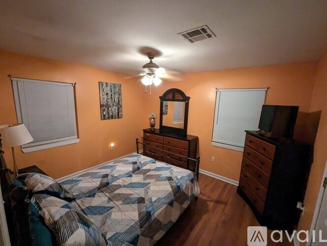 A bedroom with a bed, dresser, and ceiling fan.