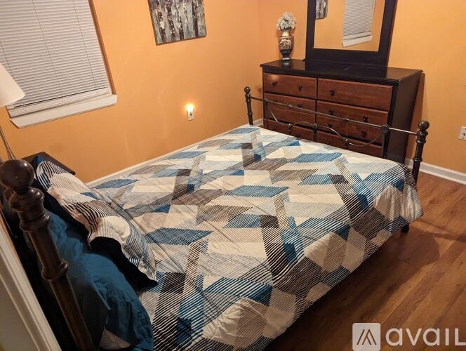 A bed with a blue and white comforter is in a room with a wooden floor.