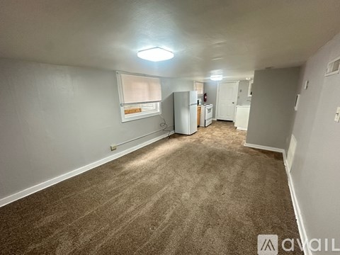 A room with a carpeted floor and a window with blinds.