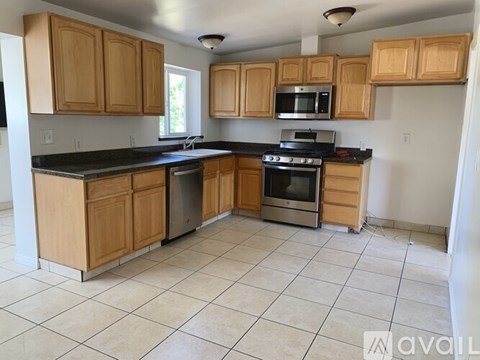 A kitchen with wooden cabinets and black countertops.