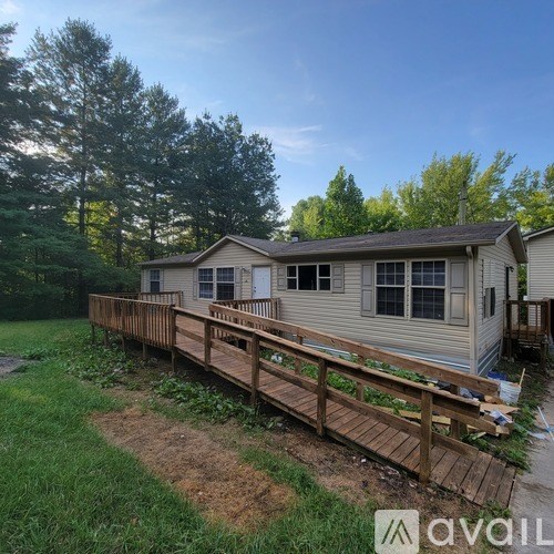 A house with a wooden deck in the foreground and trees in the background.