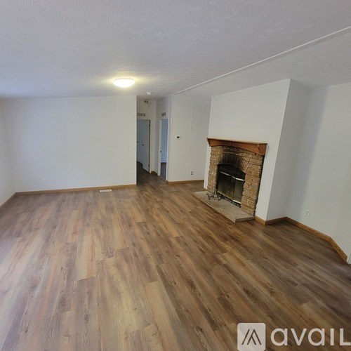 A room with wooden flooring and a fireplace.