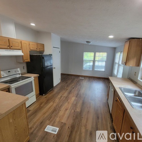 A kitchen with wooden floors and a black refrigerator.