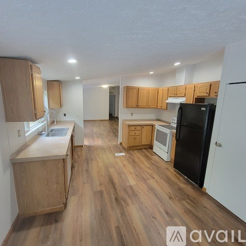 A kitchen with wooden cabinets and a black refrigerator.