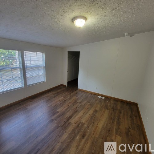 A room with wooden flooring and a window with blinds.