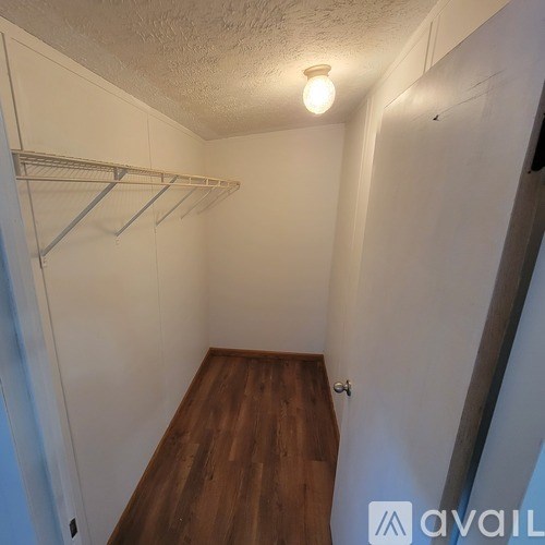 A small, empty room with a wooden floor and white walls.