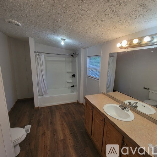 A bathroom with wooden floors and a large mirror.