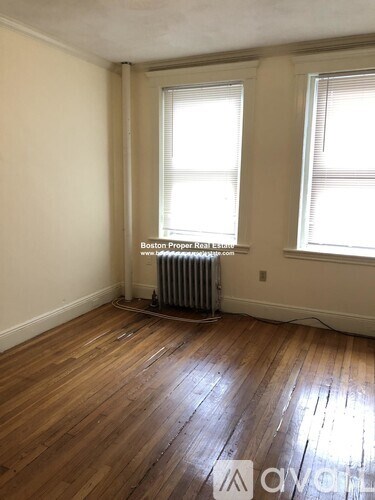A room with wooden floors and a window with blinds.