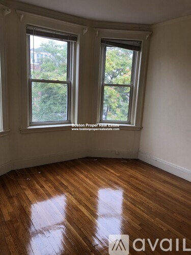 A room with wooden floors and two windows.