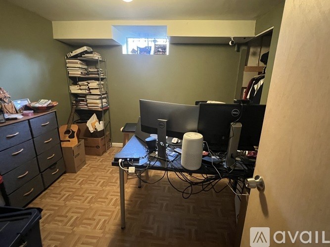 A room with a desk, computer, and a window.