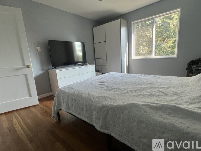 A bedroom with a bed, dresser, and television.