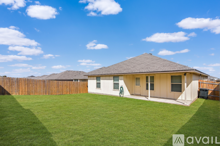 A spacious room with beige tiled flooring and a kitchen area with a counter and cabinets.