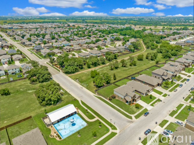 A bird's eye view of a residential area with houses, a swimming pool, and a road.
