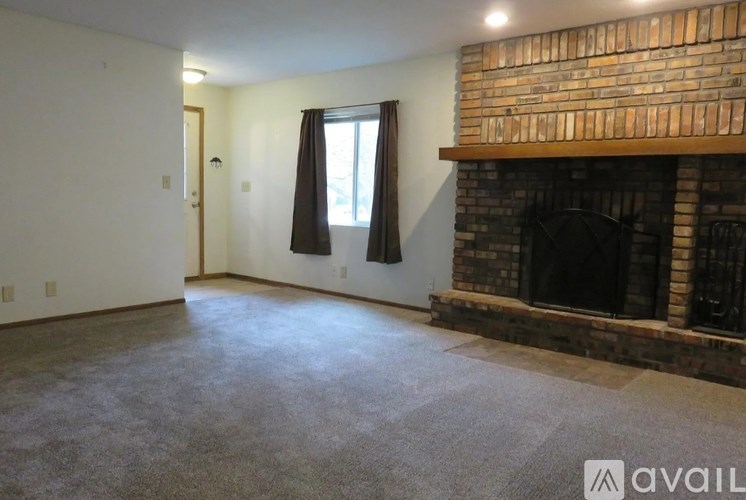A living room with a fireplace and a window with curtains.