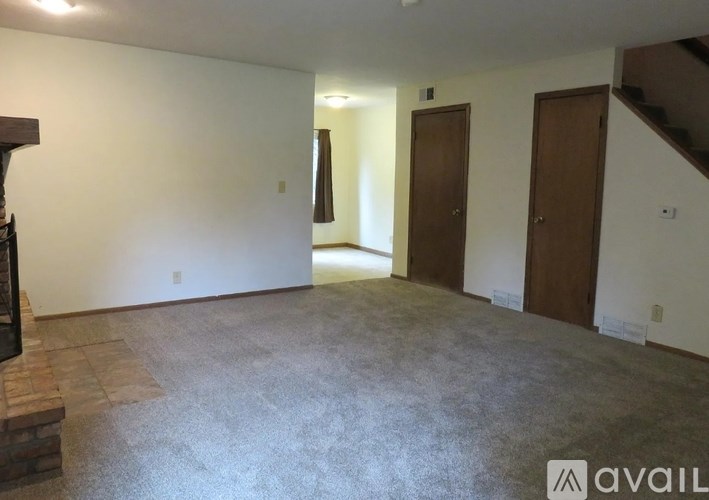 A spacious room with a staircase on the right and a door on the left.