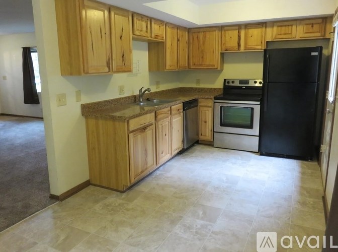 A kitchen with wooden cabinets and a black refrigerator.