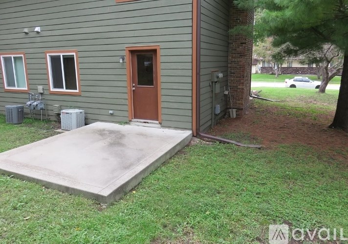 A house with a brown door and a concrete slab in front.