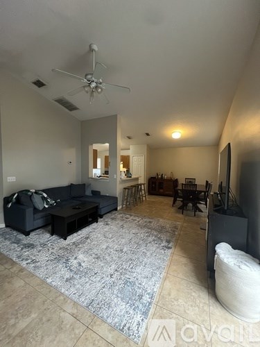 A living room with a black couch and a rug.