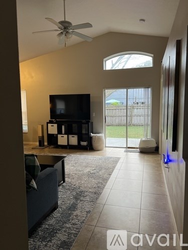 A living room with a television, a couch, and a fan.