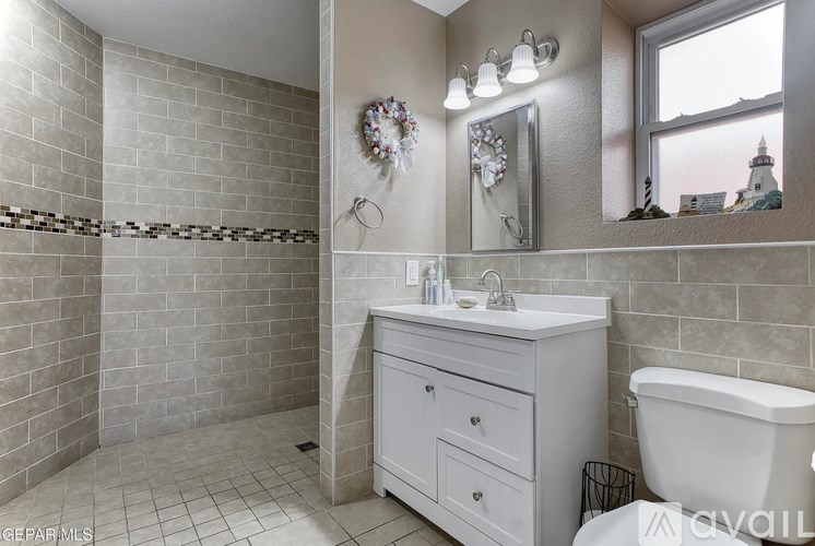 A bathroom with a white tub, sink, and tiled walls.