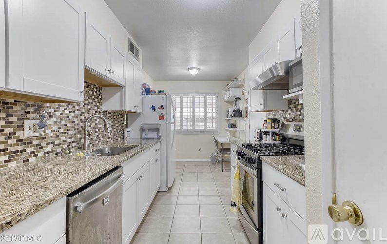 A kitchen with white cabinets and a granite counter top.