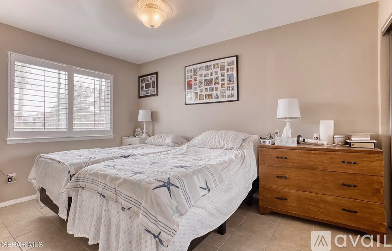 A bedroom with a bed, nightstand, and pictures on the wall.
