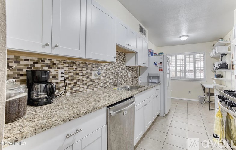 A kitchen with white cabinets and a granite countertop.