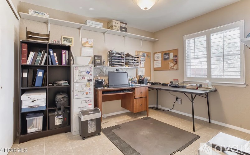 A room with a desk, a bookshelf, and a window.
