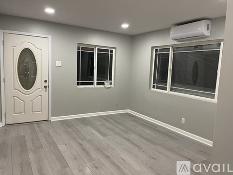 A room with a door, two windows, and a wall-mounted air conditioner.