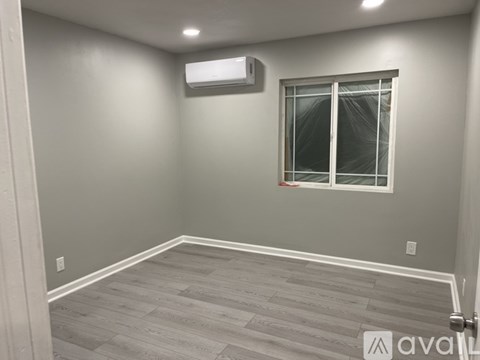 A room with a window and a wall-mounted air conditioner.
