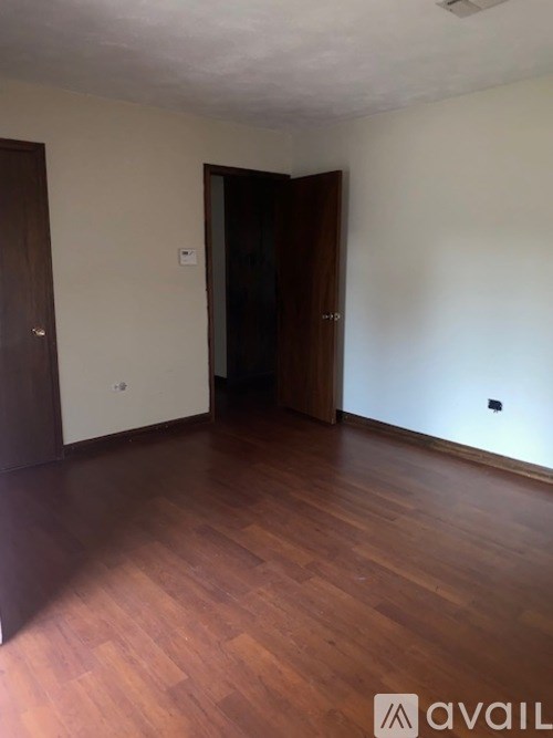 A house with a black roof and a grey car parked in front.