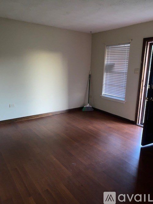 A room with wooden floors and a window with blinds.