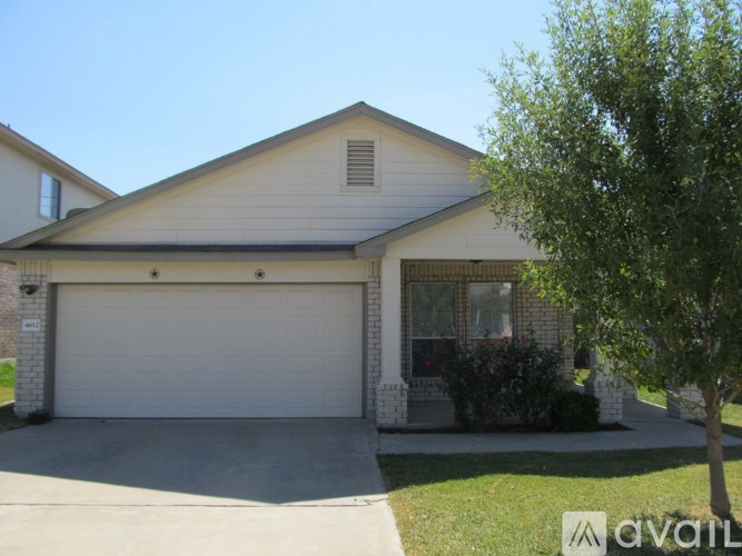 A house with a white garage door and a tree in front.