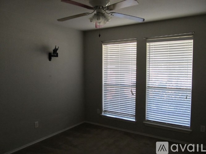 A room with a ceiling fan and two windows with blinds.
