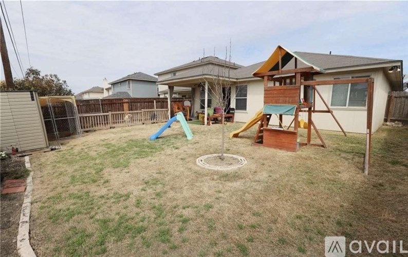 A backyard with a playground and a house in the background.