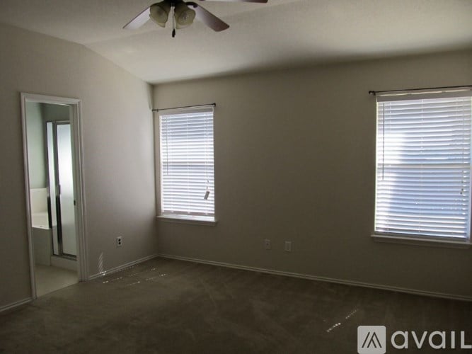 A room with a ceiling fan and two windows.
