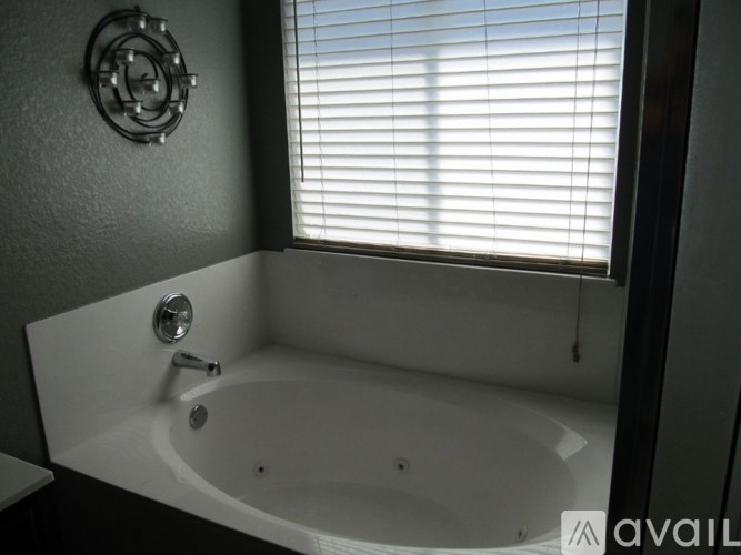 A white bathtub with a silver faucet and a round mirror on the wall.