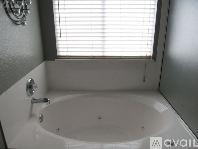 A white bathtub with a silver faucet is in a bathroom with a window above it.