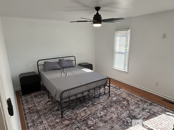 A bedroom with a bed, pillows, a ceiling fan, and a rug.