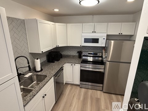 A modern kitchen with white cabinets and stainless steel appliances.