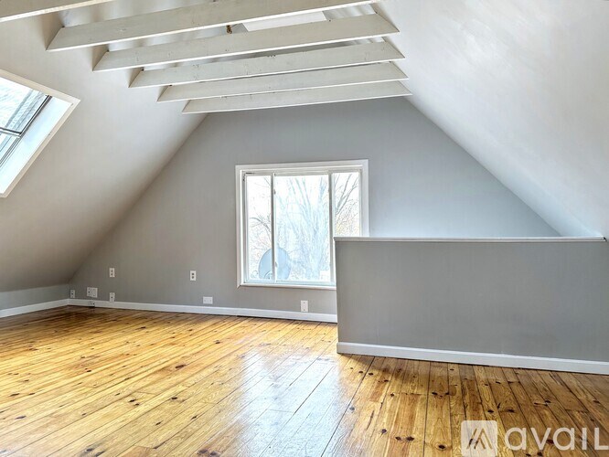 A room with wooden floors and a window with a view of trees.