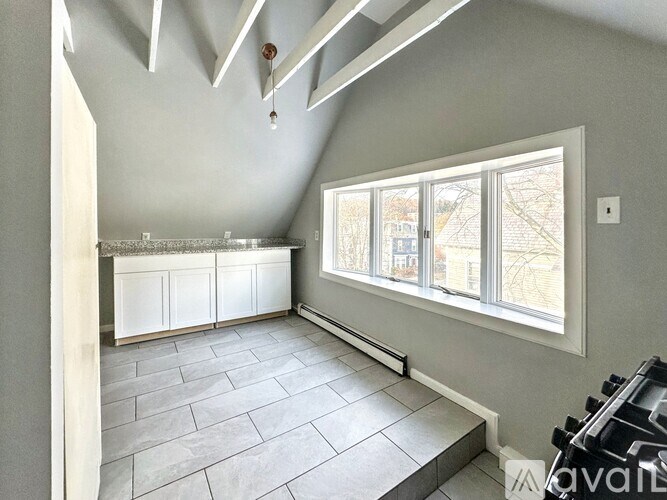 A room with a large window and a stone floor.