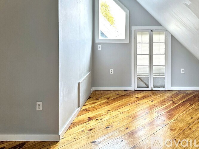 A room with wooden floors and a window with blinds.