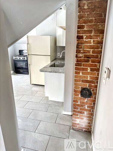 A kitchen with a brick wall and a white fridge.