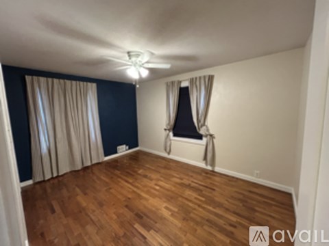 A room with wooden floors and a window with curtains.