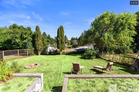A backyard with a lawn, two chairs, and a fire pit.