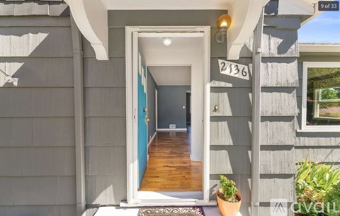 A house numbered 2136 with a blue door and a plant on the porch.