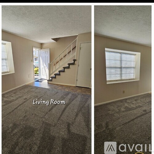 A living room with a carpeted floor and a staircase.