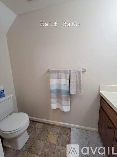 A half bathroom with a toilet, a towel rack with a striped towel, and a sink.