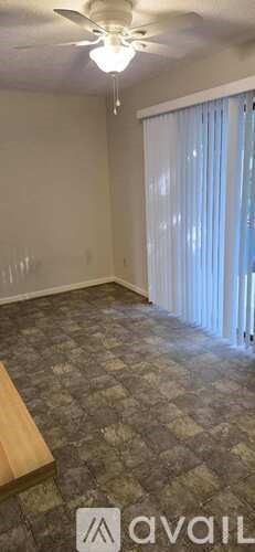 A room with a ceiling fan and a window with curtains.